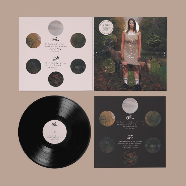 in front of an alt rose background we see layed out the components of the vinyl release of the album 4 in a Cycle of Thirds by Alev lenz. They are layed out in a square with the top left being the back of the record, 6 circles showing parts of the oil painting, the sky, the ivory tower and the forest floor and in the middle the album tracklisting. the top left corner is the front over of the album ,a hybrid of alev lenz standing in a clearing on a forest path, her body painted, mountain goest behind her painted , all in oil. overlayered by six cricles again showing the photogrpahy the painting was made from. we see her face as a photo, her calves and the four circles to the lef and right are of the trees, however not covering the painted goats horns, and the forrest floor. below on the lower right is the inlay which is exactly a copy of the back of the record but in black with the tracklsiting of the drone versions of the album. and finally to the low left is the round black vinyl, with an alt rose sticker with the side and tracklist on it.